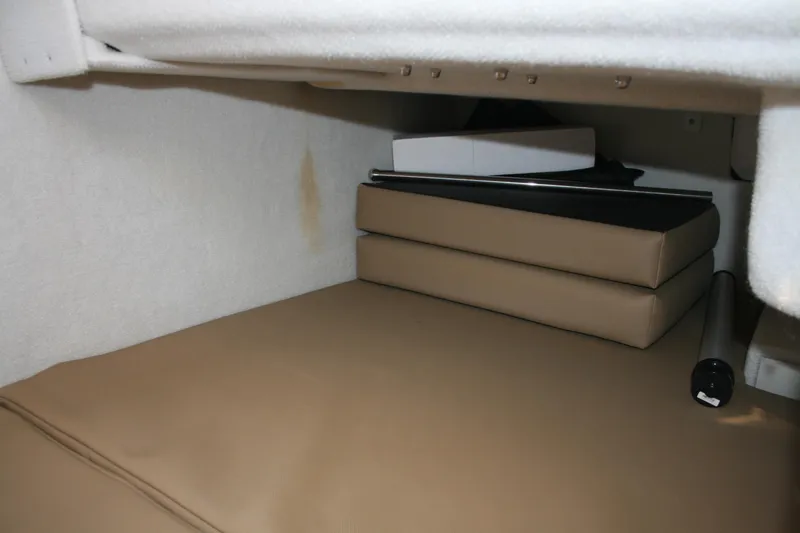 Slide: The Image of 2024 Ranger Tugs R-25 interior storage area with stacked cushions and white walls. - 20