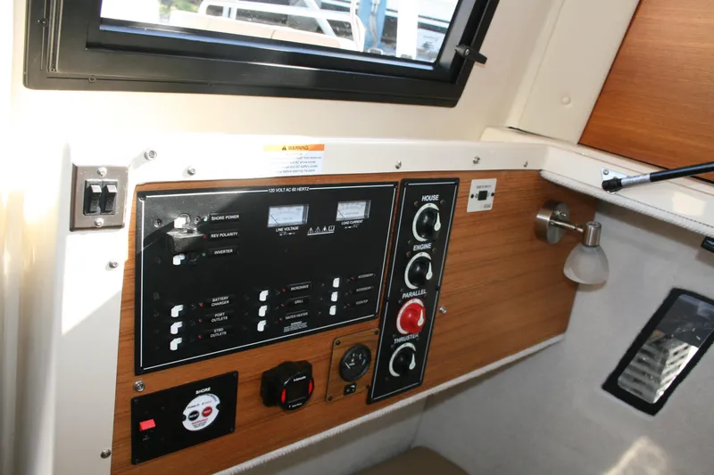 Slide: The Image of 2024 Ranger Tugs R-25 control panel with switches and gauges in cabin interior. - 21