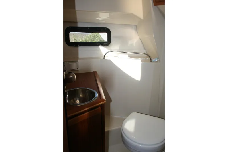 Slide: The Image of 2024 Ranger Tugs R-25 boat bathroom with sink, toilet, and window. - 22