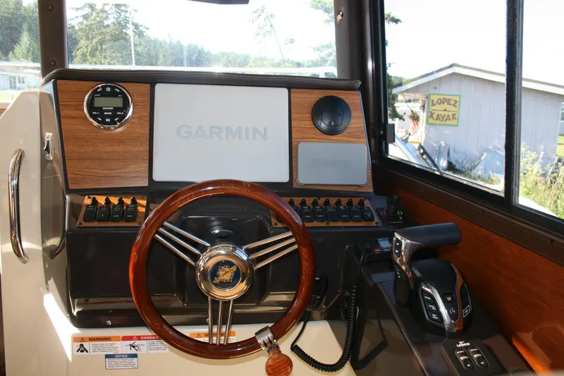 Slide: The Image of 2024 Ranger Tugs R-25 helm with Garmin navigation, wooden steering wheel, and control panel. - 4