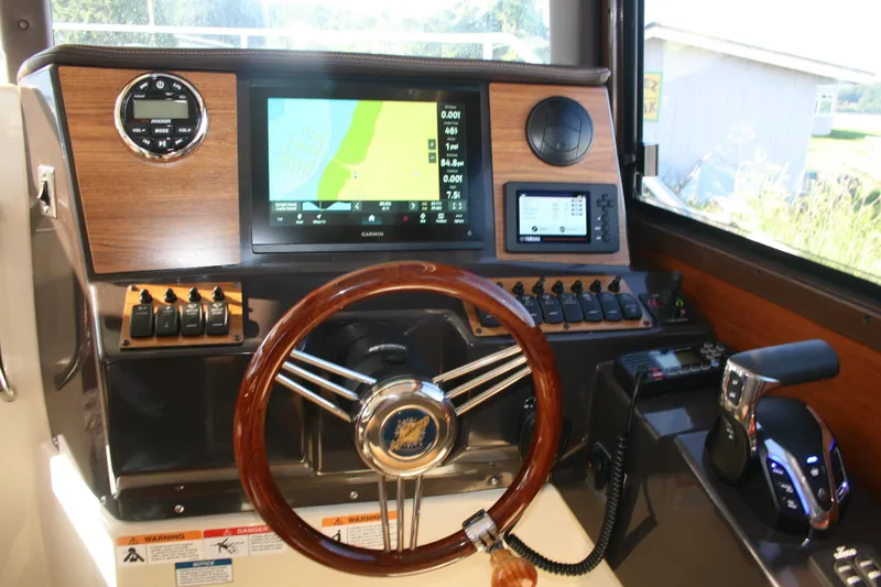 Slide: The Image of 2024 Ranger Tugs R-25 helm with navigation display and wooden steering wheel. - 5