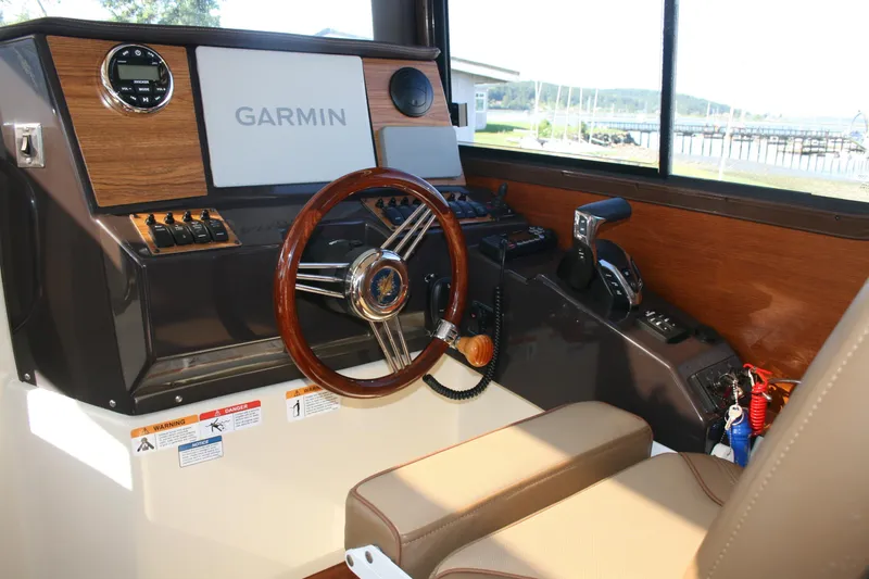 Slide: The Image of 2024 Ranger Tugs R-25 helm with Garmin navigation, wood accents, and leather seating. - 6