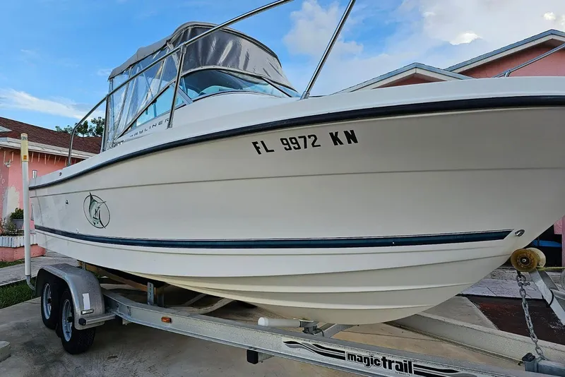 The Image of 1999 Bayliner 1802 Trophy boat on trailer, parked near a pink house. - 0