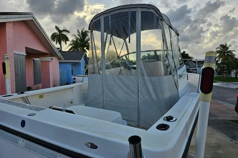 Slide: The Image of 1999 Bayliner 1802 Trophy boat with canopy, parked near colorful houses and palm trees. - 5