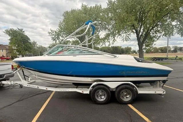 Slide: The Image of 2007 Regal 2200 Bowrider boat on trailer, parked outdoors with trees in background. - 2