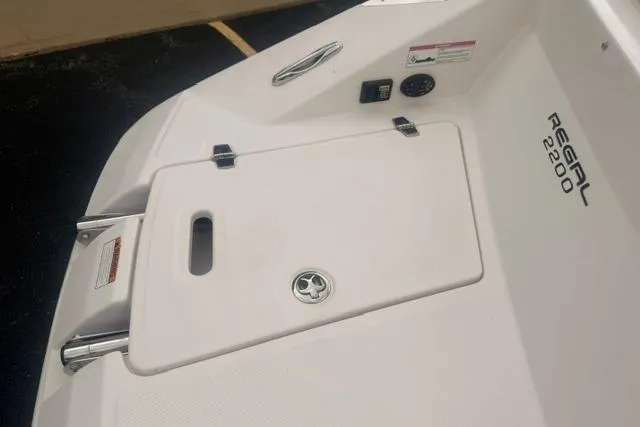 Slide: The Image of 2007 Regal 2200 Bowrider boat deck with storage compartment and branding. - 29