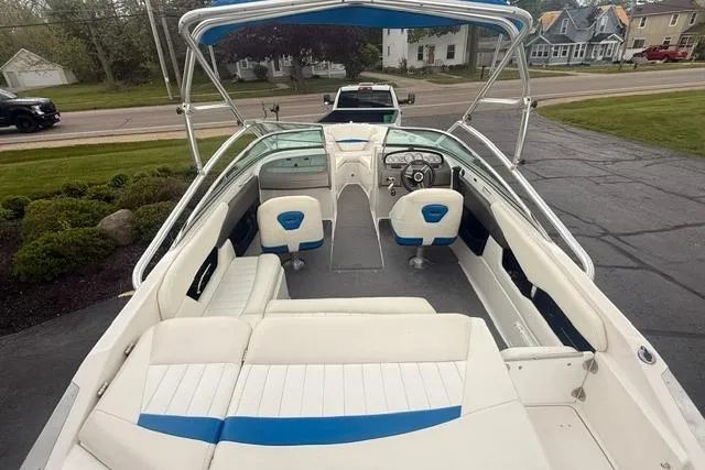 Slide: The Image of 2007 Regal 2200 Bowrider boat with white and blue interior, parked on driveway. - 4