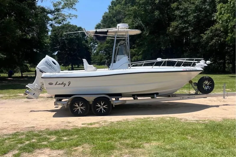 The Image of 2002 Triumph 210 CC boat on trailer with Suzuki outboard motor, parked outdoors. - 1