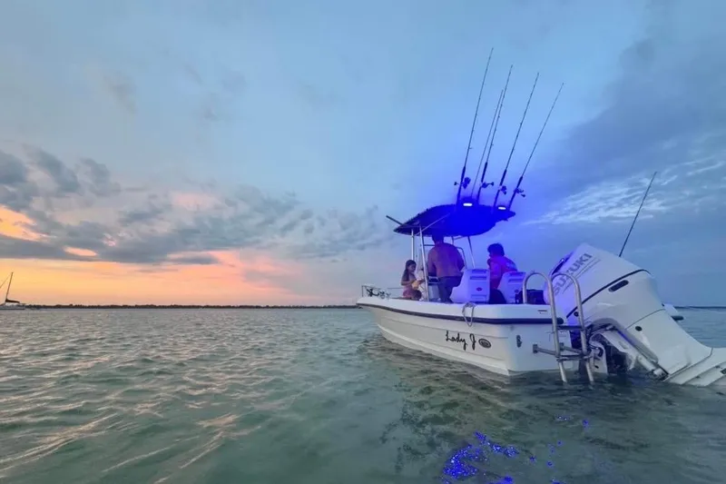 Slide: The Image of 2002 Triumph 210 CC boat on water at sunset with fishing rods. - 10