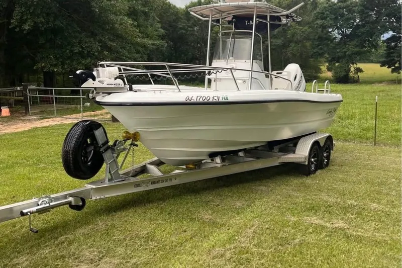 Slide: The Image of 2002 Triumph 210 CC boat on trailer, parked on grassy field. - 3