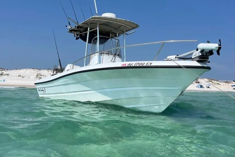 Slide: The Image of 2002 Triumph 210 CC boat anchored in clear turquoise water near a sandy beach. - 4