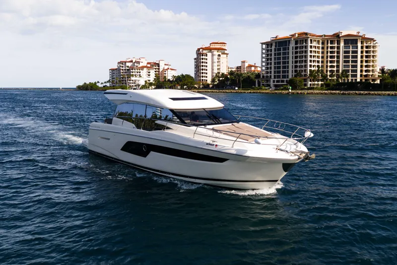 The Image of 2023 Prestige 520S yacht cruising near waterfront buildings under a clear sky. - 0