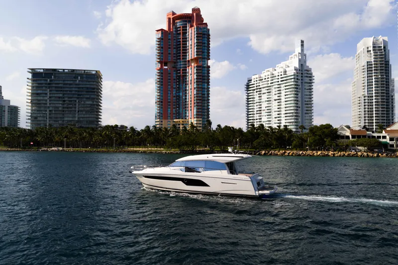 Slide: The Image of 2023 Prestige 520S yacht cruising near modern city skyline. - 2