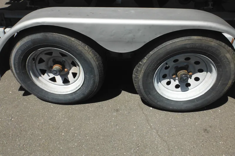 Slide: The Image of Trailer wheels for 1998 Wellcraft 23 Excel boat on asphalt surface. - 49