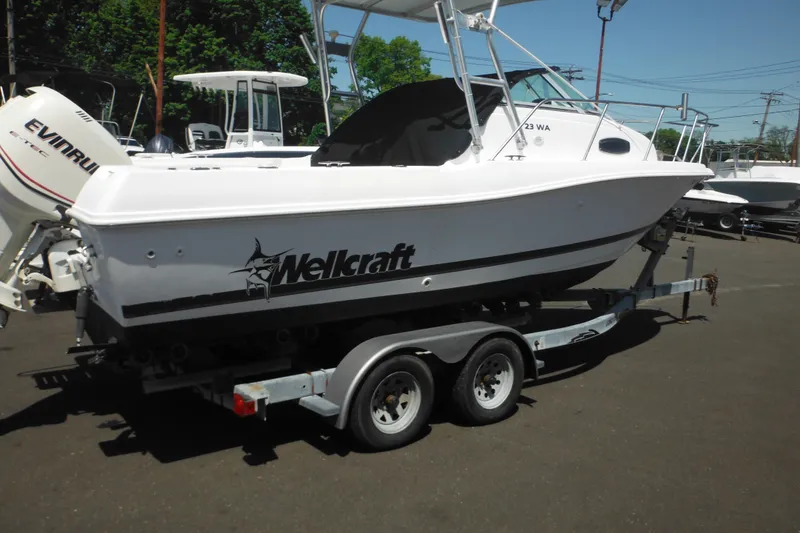 Slide: The Image of 1998 Wellcraft 23 Excel boat on trailer, featuring Evinrude engine, parked outdoors. - 8