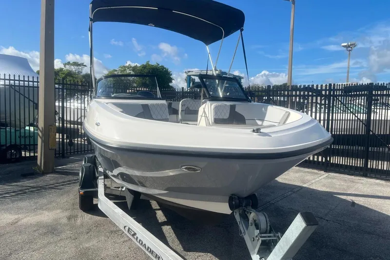 Slide: The Image of 2023 Bayliner VR5 Bowrider OB on trailer, parked outdoors under blue sky. - 4