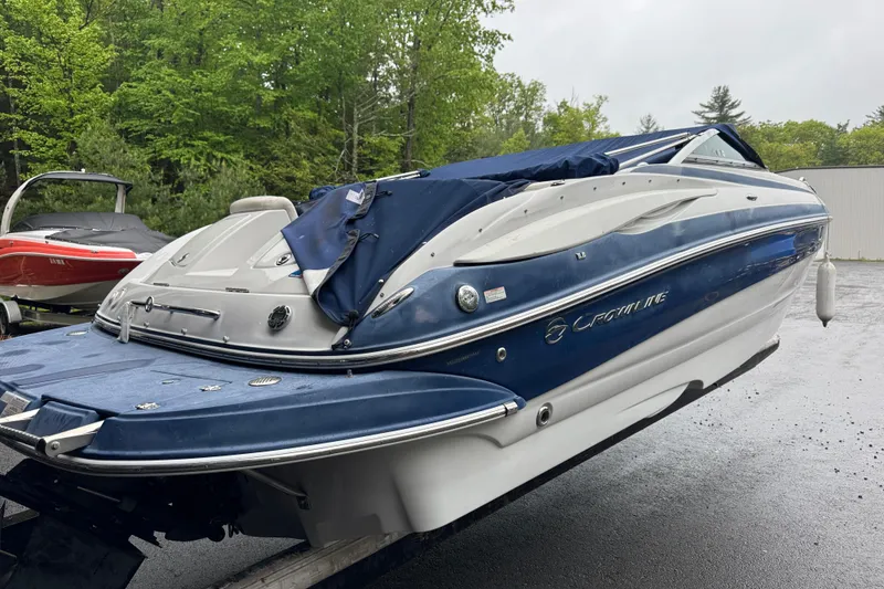Slide: The Image of 2009 Crownline 240 LS boat with blue cover, parked outdoors on a rainy day. - 3