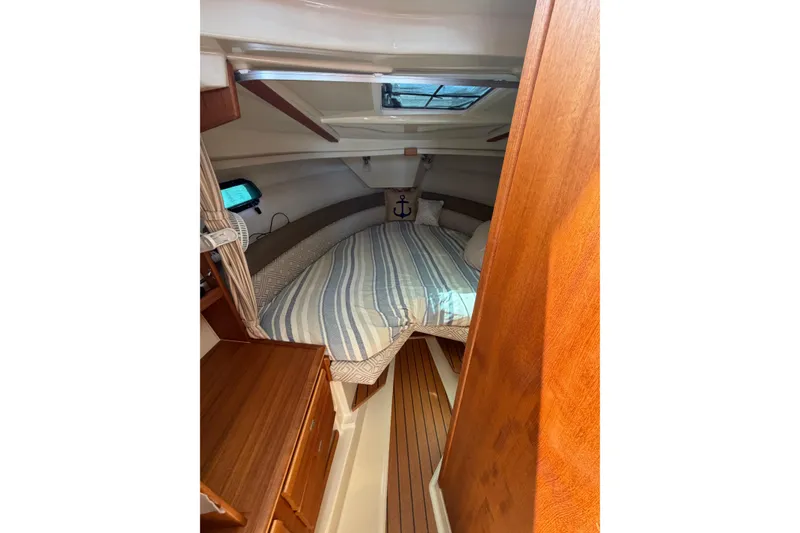 Slide: The Image of 2021 Ranger Tugs R-27 cabin interior with cozy bed and wooden furnishings. - 14