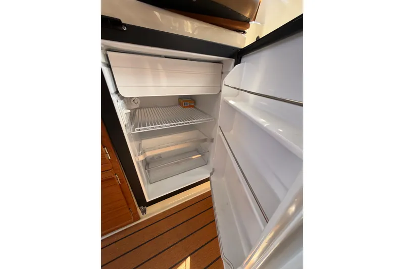Slide: The Image of Open refrigerator inside 2021 Ranger Tugs R-27 boat, featuring wooden flooring. - 17