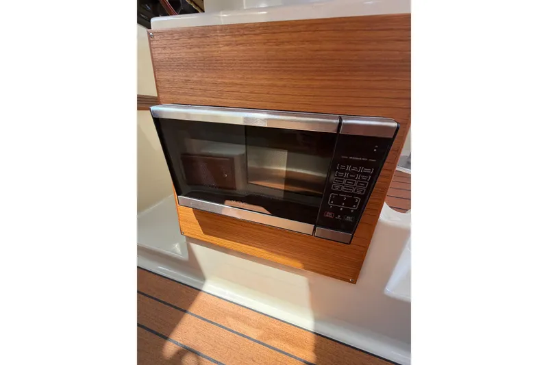 Slide: The Image of Built-in microwave in 2021 Ranger Tugs R-27 boat interior, featuring wood paneling. - 18
