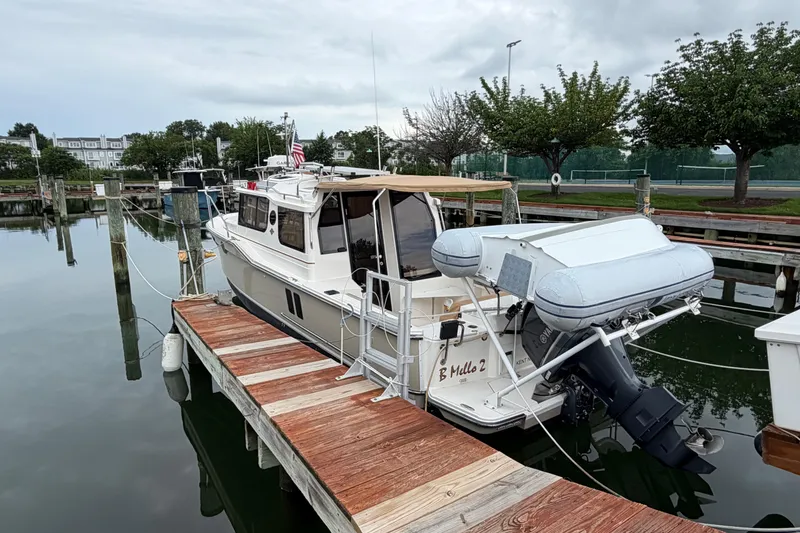 Slide: The Image of 2021 Ranger Tugs R-27 docked, featuring an outboard motor and inflatable dinghy. - 2