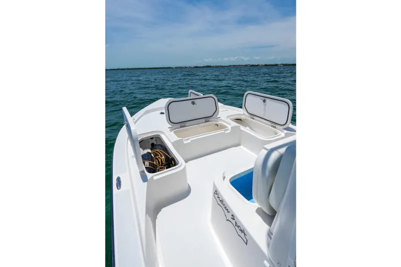 Slide: The Image of 2022 Shallow Sport 24 Modified V boat with open storage compartments on calm water. - 15
