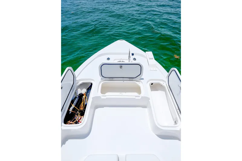Slide: The Image of 2022 Shallow Sport 24 Modified V boat deck with open storage compartments on the water. - 16