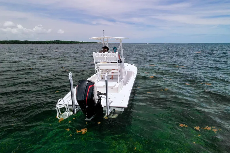 Slide: The Image of 2022 Shallow Sport 24 Modified V boat on clear ocean water under blue sky. - 2
