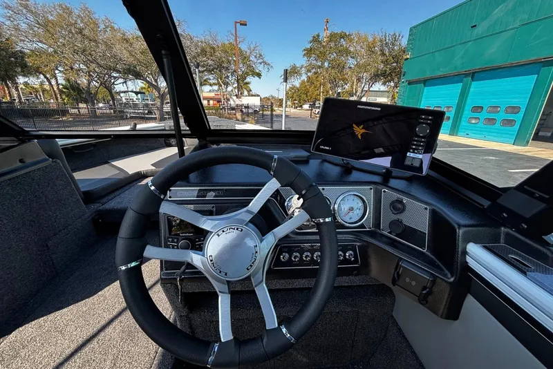 Slide: The Image of 2026 Lund 1875 Crossover XS boat dashboard with steering wheel and navigation display. - 12