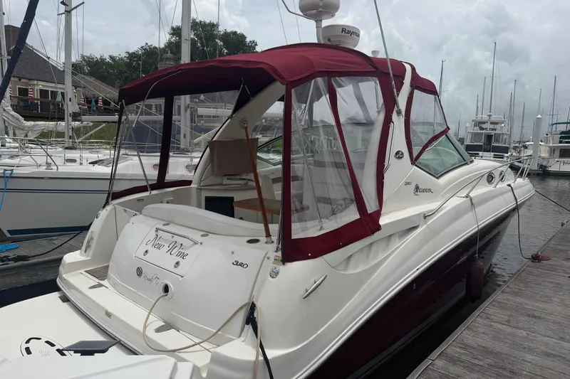 Slide: The Image of 2006 Sea Ray Sundancer 320 docked, featuring maroon canopy and sleek white design. - 3