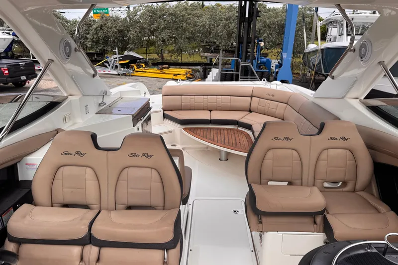 Slide: The Image of 2016 Sea Ray SLX 350 boat interior with tan leather seating and wooden table. - 18