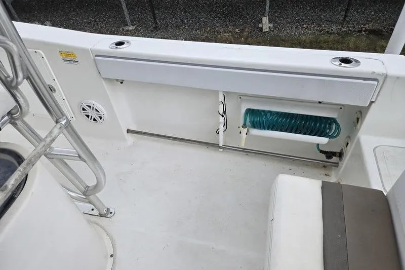 Slide: The Image of 2011 Sea Hunt Triton 240 boat deck with storage compartment and coiled hose. - 19