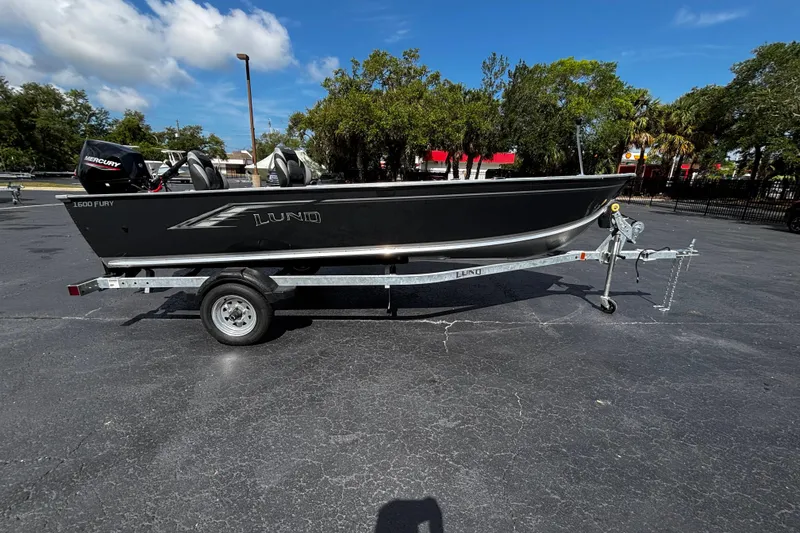 The Image of 2026 Lund 1600 Fury Tiller boat on trailer, parked outdoors under blue sky. - 1