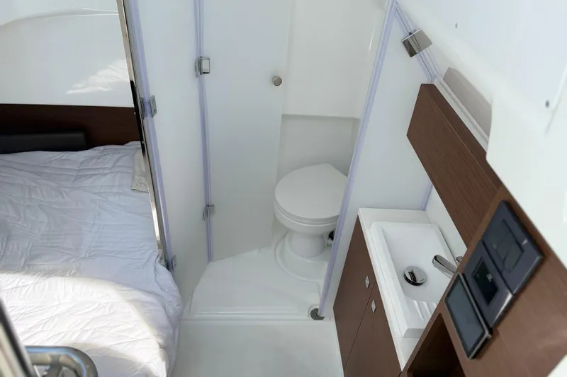 Slide: The Image of 2026 Wellcraft 38 T-Top cabin interior with bed, compact bathroom, and sink. - 13