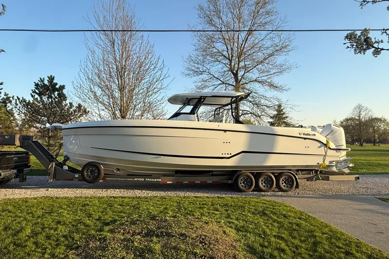 Slide: The Image of 2026 Wellcraft 38 T-Top boat on trailer, parked outdoors in a scenic setting. - 2