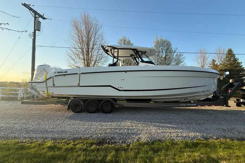 Slide: The Image of 2026 Wellcraft 38 T-Top boat on trailer, parked outdoors, side view. - 3