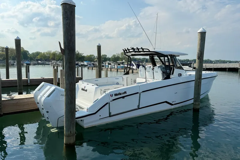 Slide: The Image of 2026 Wellcraft 38 T-Top boat docked in a marina under a cloudy sky. - 32