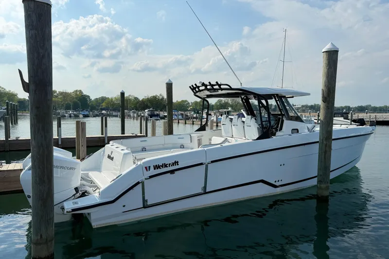 Slide: The Image of 2026 Wellcraft 38 T-Top boat docked in a marina under a partly cloudy sky. - 35