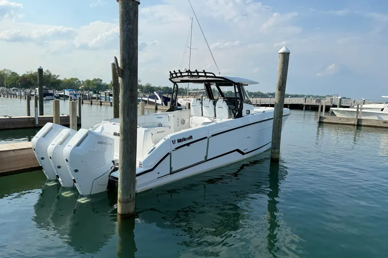 Slide: The Image of 2026 Wellcraft 38 T-Top boat docked in a marina with triple Mercury engines. - 36