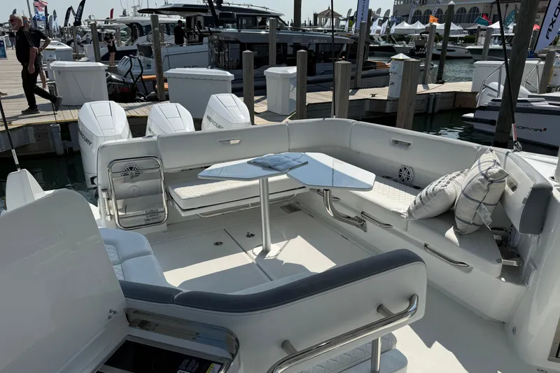 Slide: The Image of 2026 Wellcraft 38 T-Top boat interior with seating and table at a marina. - 6