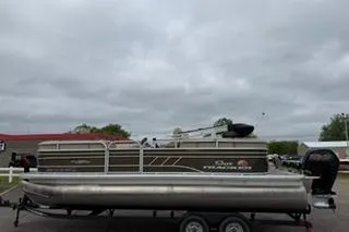 The Image of 2022 SUNTRACKER Party Barge 22 pontoon boat on trailer under cloudy sky. - 1