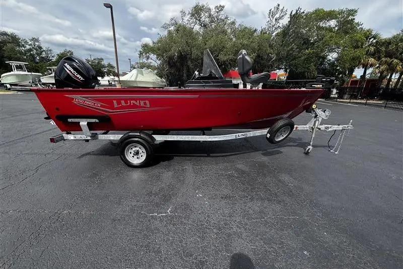 Slide: The Image of 2026 Lund 1650 Angler SS boat on trailer, red exterior, parked outdoors. - 1