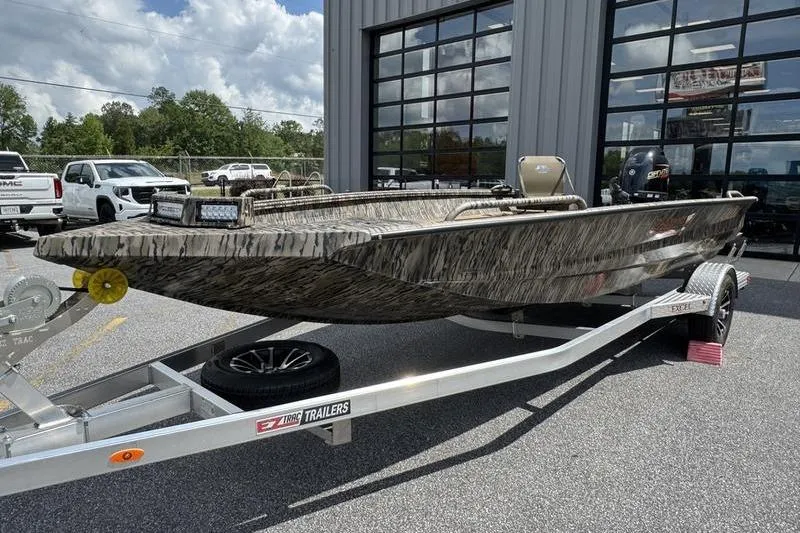 The Image of 2026 Excel 183 Tomahawk boat on trailer outside dealership, featuring camouflage design. - 0
