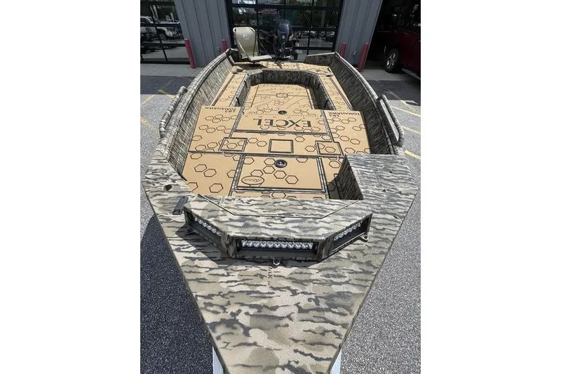Slide: The Image of 2026 Excel 183 Tomahawk boat with camouflage design, parked outdoors. - 2