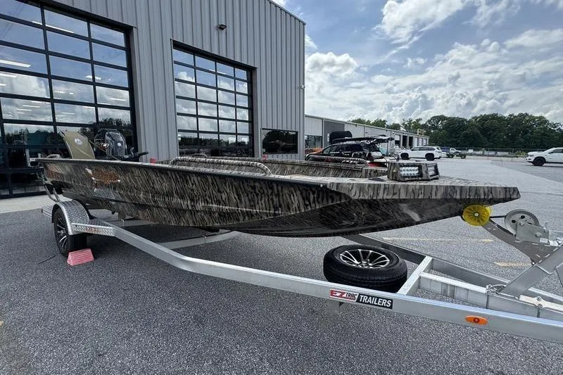 Slide: The Image of 2026 Excel 183 Tomahawk boat on trailer outside industrial building under cloudy sky. - 21