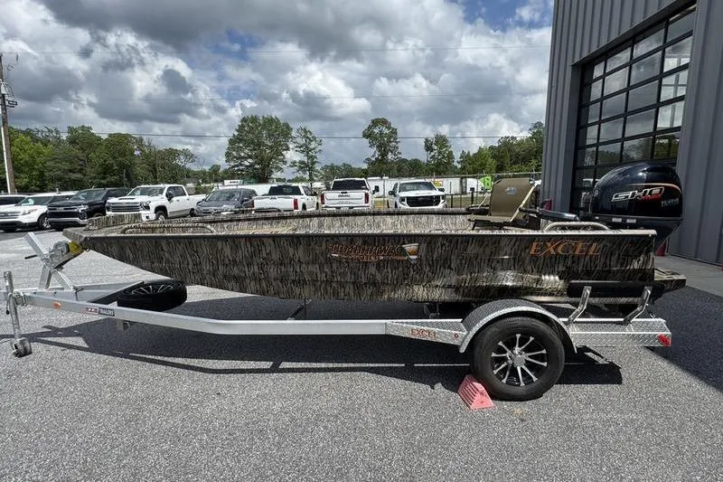 Slide: The Image of 2026 Excel 183 Tomahawk boat on trailer, parked outdoors under cloudy sky. - 25