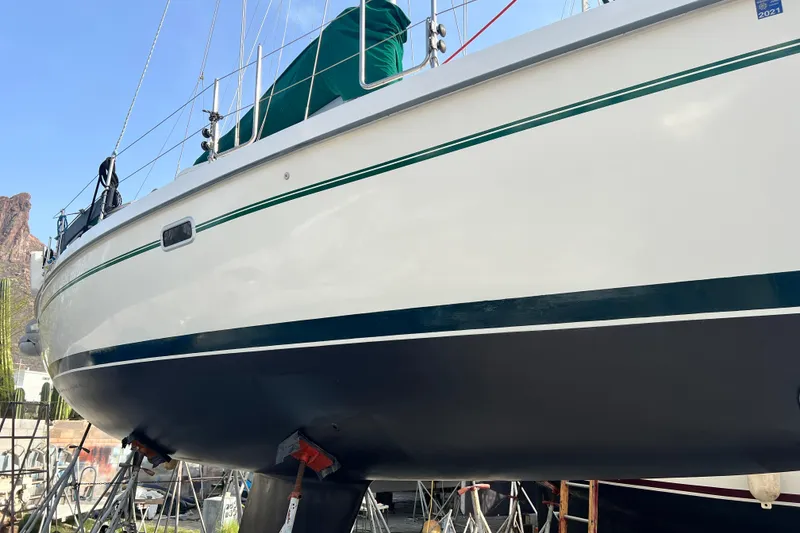 Slide: The Image of 1999 Catalina 380 sailboat on stands, with green trim and blue hull, outdoors. - 16