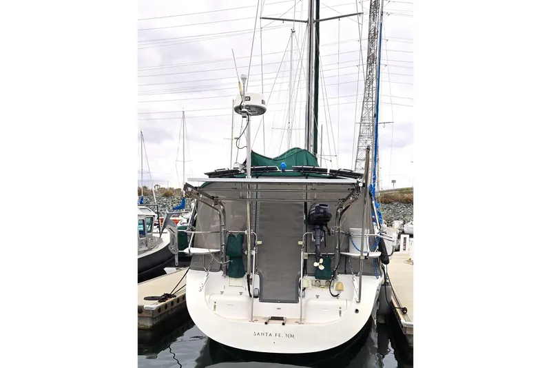 Slide: The Image of 1999 Catalina 380 sailboat docked at marina, rear view with equipment visible. - 19