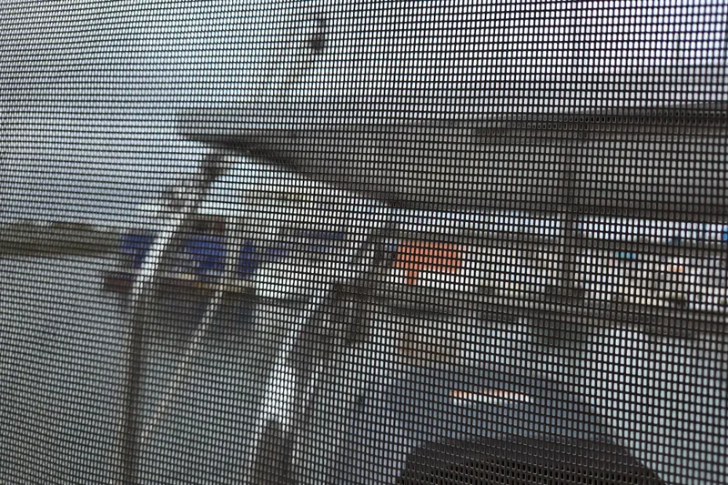 Slide: The Image of Blurred view through mesh screen of a marina with boats, including a 1999 Catalina 380. - 26