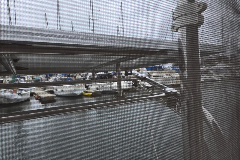 Slide: The Image of Marina view through mesh screen, featuring docked boats and overcast sky. Catalina 380, 1999. - 27